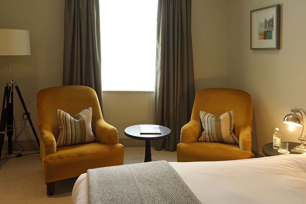 Elegant superior room at Kings Head Hotel, featuring plush white bedding, refined wooden furniture, and soft neutral color palette with warm accent lighting