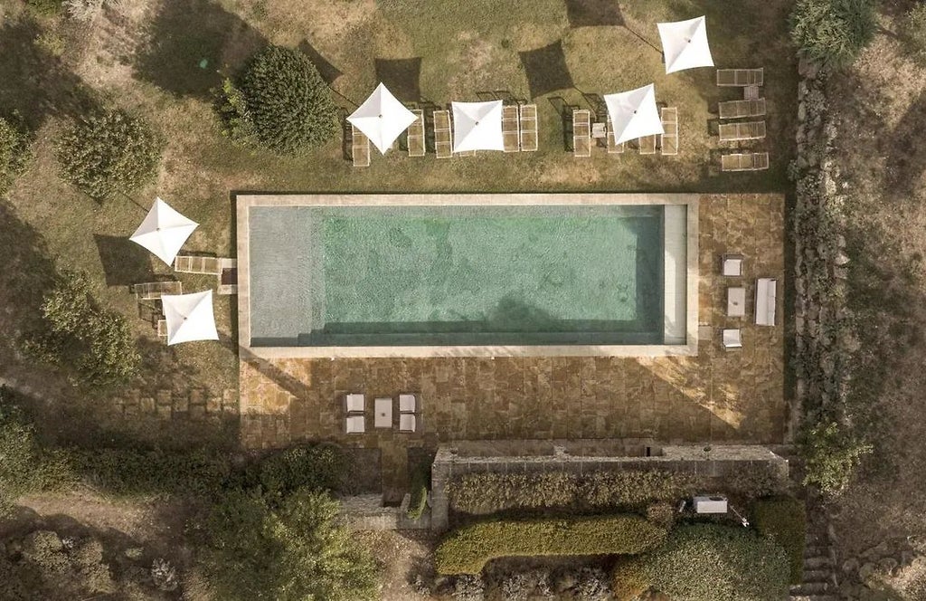 Elegant stone facade of Le Galinier hotel in Provence, with rustic terracotta roof, lush greenery, and warm golden sunlight filtering through cypress trees