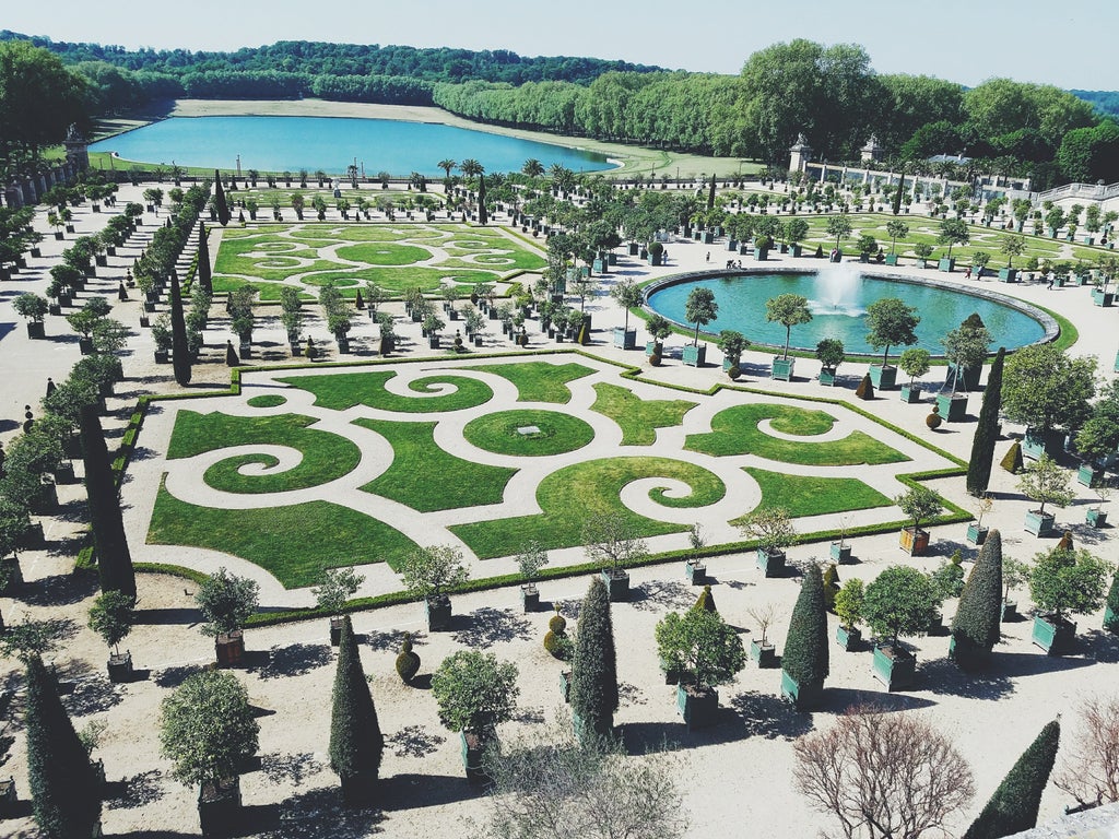 Opulent golden gates of Versailles Palace, sunlight gleaming on ornate baroque architecture and manicured gardens of French royal estate