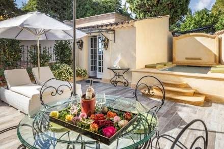 Elegant French Provencal hotel room with antique furnishings, soft blue walls, ornate chandelier, and plush white linens at luxury accommodation