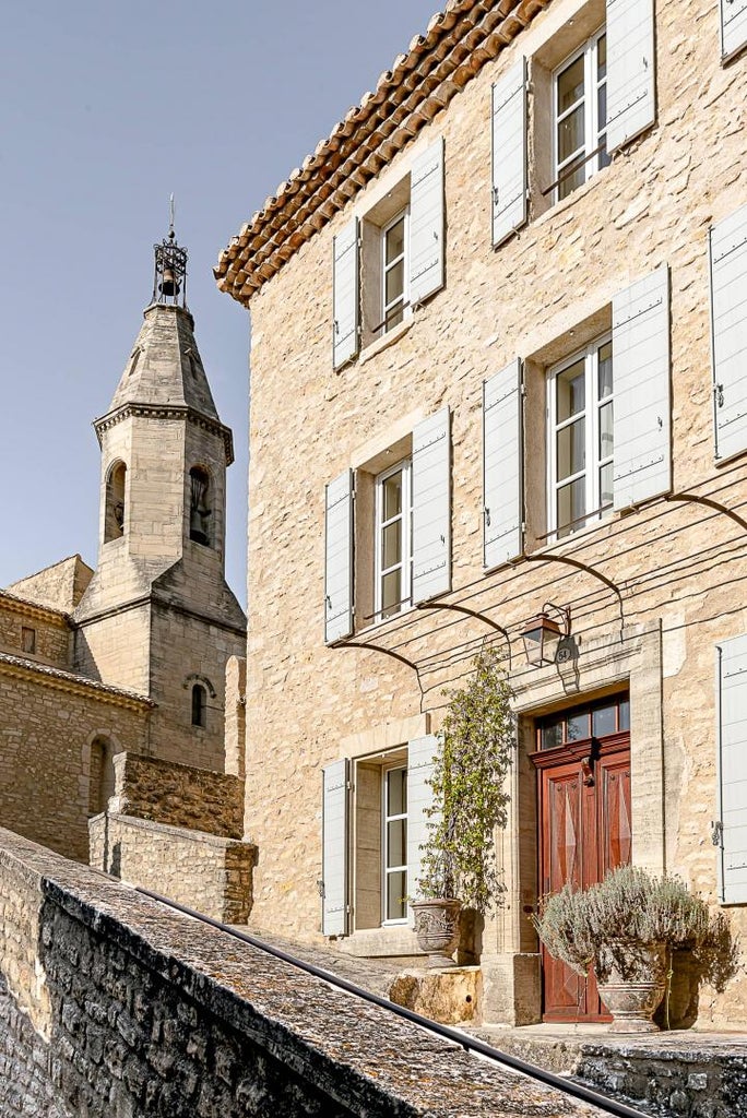 Elegant stone facade of Hotel Crillon Le Brave with traditional French shutters, nestled in the Provençal countryside at sunset