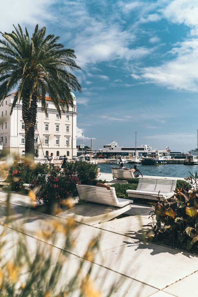 Small group follows tour guide through charming cobblestone streets of Dubrovnik's Old Town, passing historic stone buildings and scenic archways