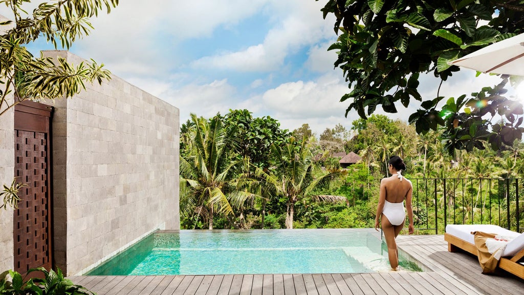 Luxurious Balinese villa suite with private infinity pool surrounded by tropical jungle, featuring terrace and sun loungers