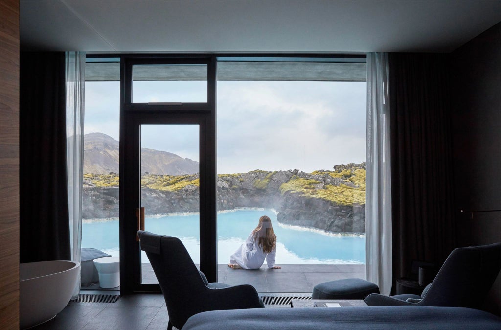 Luxurious modern hotel nestled in scenic Icelandic landscape, featuring minimalist design with floor-to-ceiling windows overlooking dramatic volcanic terrain