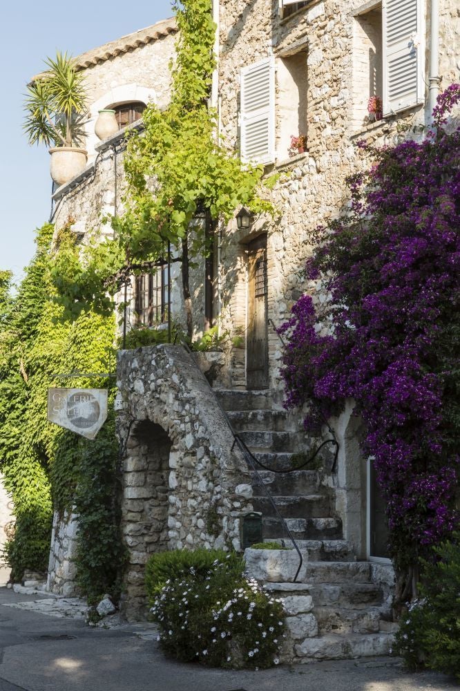 Elegant stone facade of historic boutique hotel with arched windows, nestled in a charming French village street with cobblestone pathway