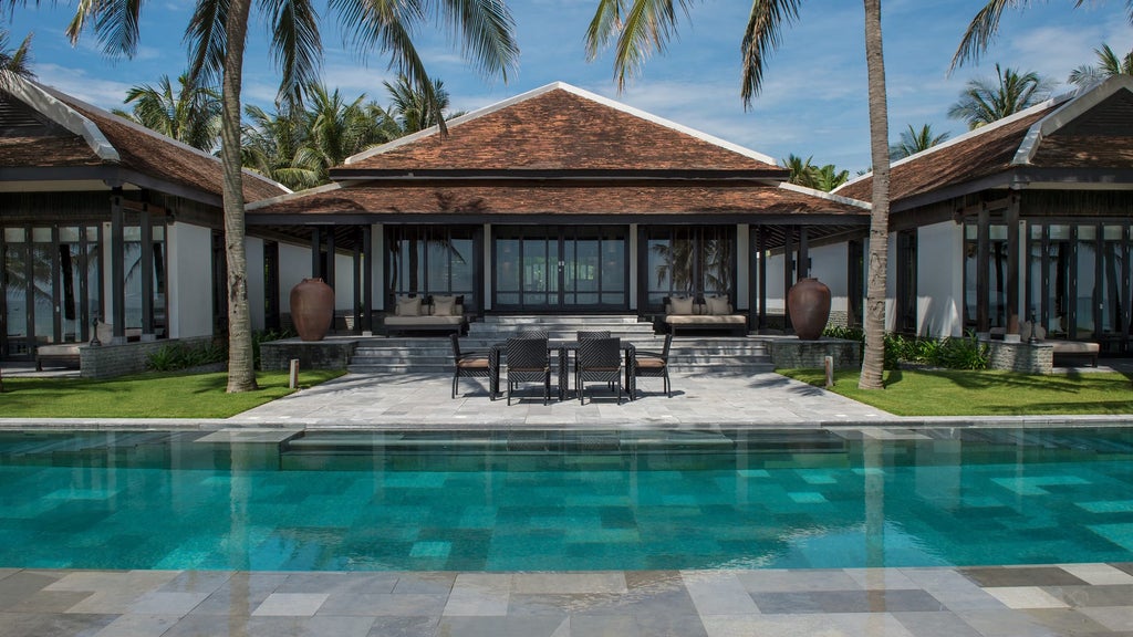 Luxurious beachfront villa at Four Seasons Nam Hai with infinity pool merging into ocean views, surrounded by tropical gardens at sunset