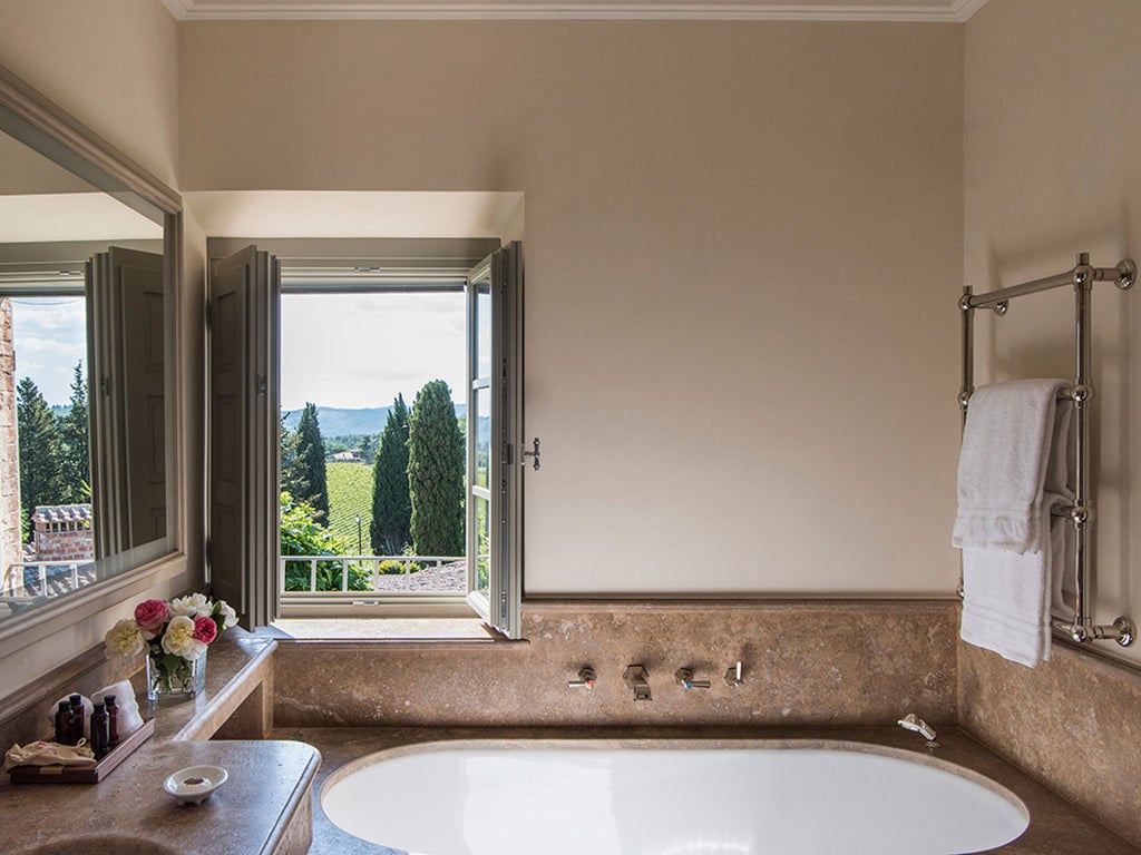 Elegant Tuscan luxury hotel nestled among vineyards, featuring stone buildings with terracotta roofs and manicured Mediterranean gardens