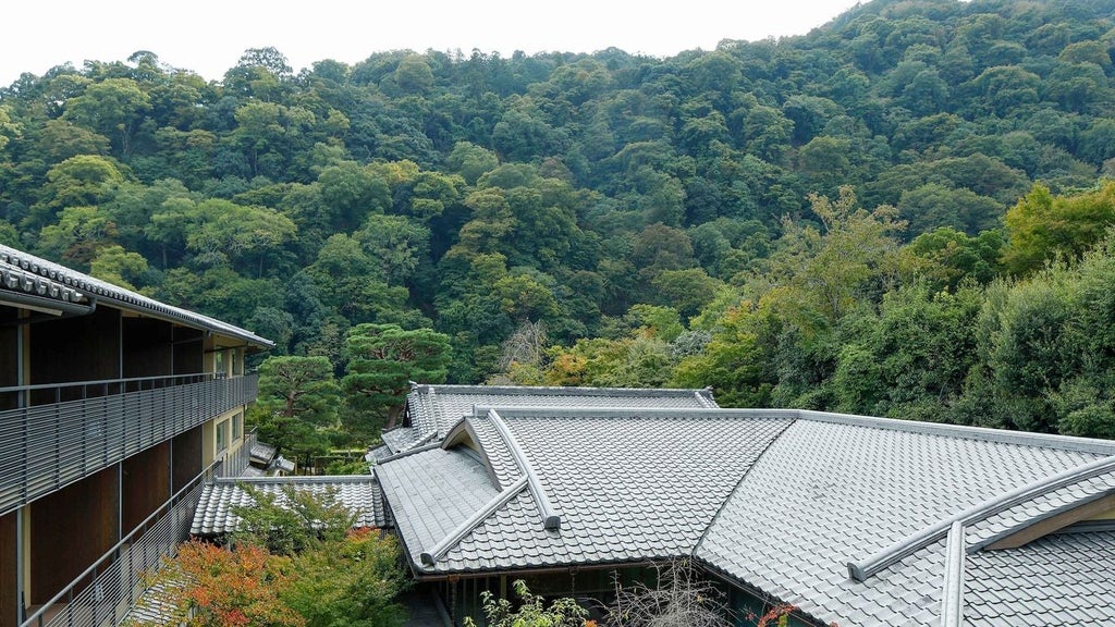 Elegant traditional Japanese ryokan-style luxury hotel nestled by tranquil Kyoto river, featuring wooden architecture, serene garden, and soft evening light