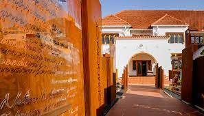 Elegant hotel façade with contemporary African design, featuring stone walls, expansive glass windows and manicured garden landscaping