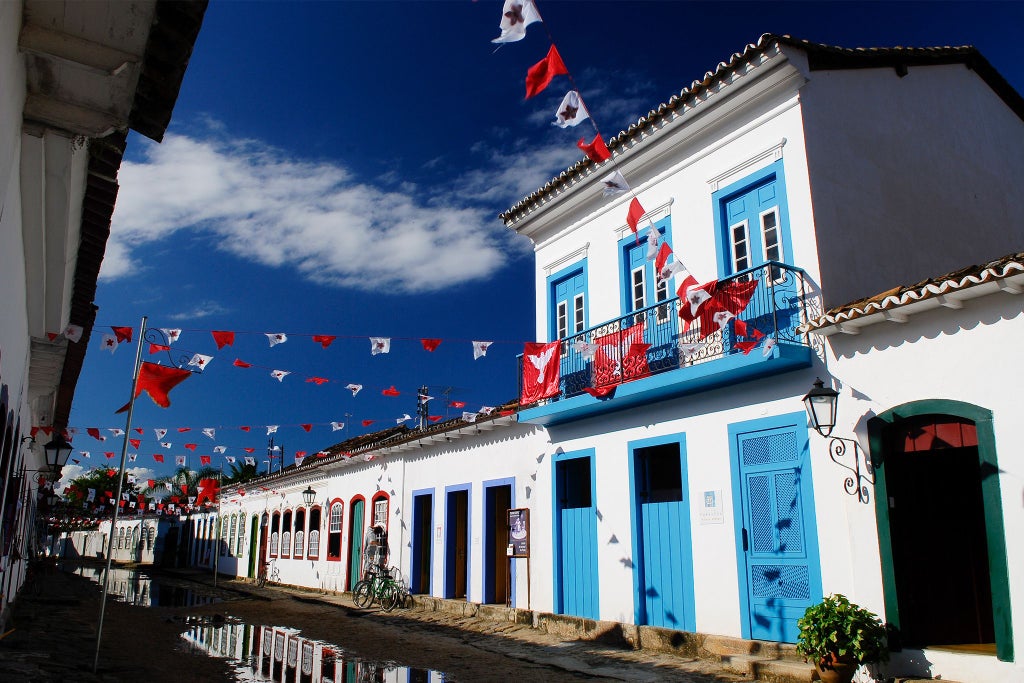 Luxurious turquoise-blue colonial boutique hotel in Paraty, Brazil, with elegant white-trimmed windows and lush tropical garden setting