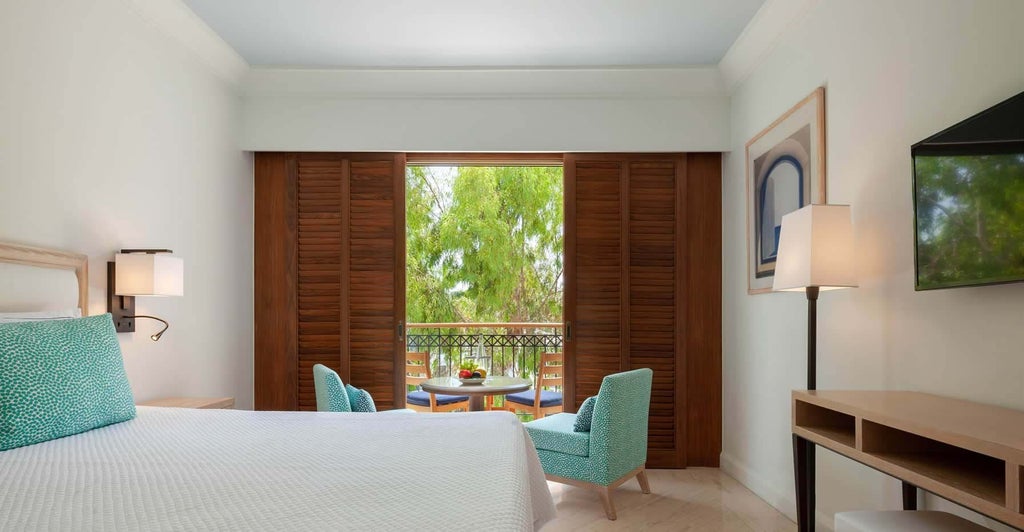 Elegant inland view hotel room with plush white bedding, modern minimalist decor, warm wood accents, and expansive window overlooking scenic Cyprus landscape