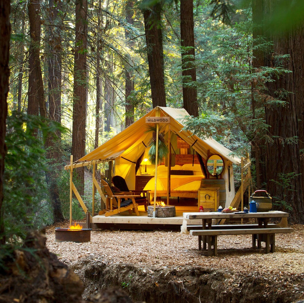 Luxurious safari-style tent nestled in Big Sur forest with private deck, canvas walls, and high-end outdoor furnishings at dusk