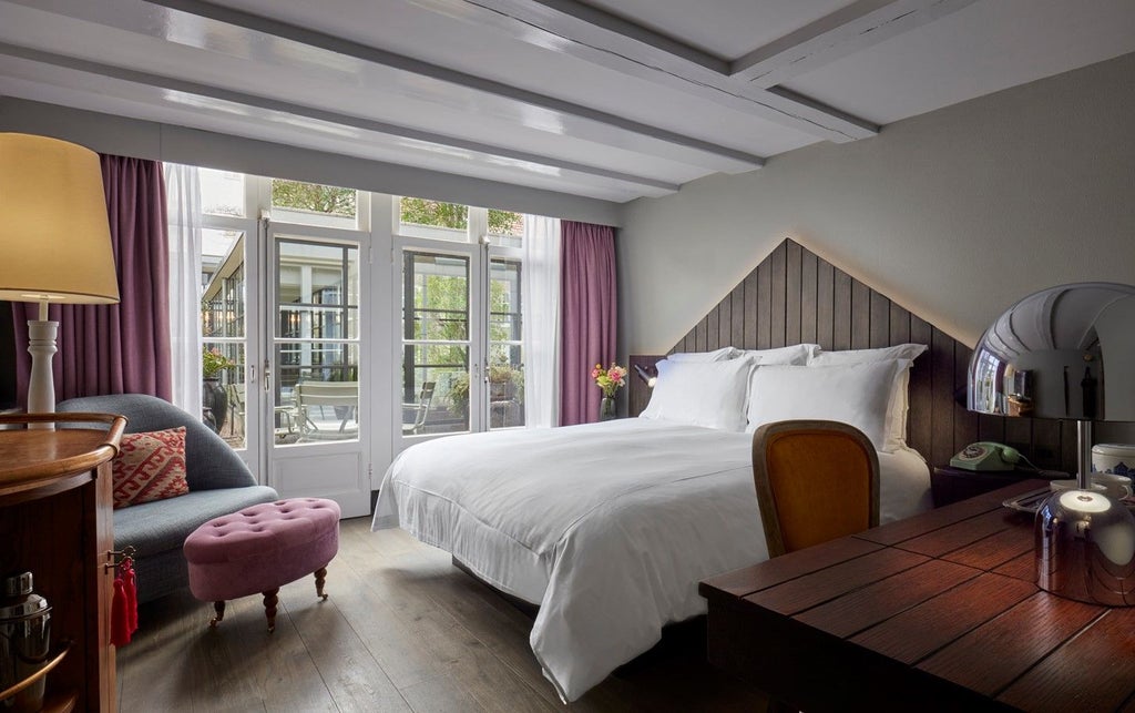 Elegant hotel room with antique furnishings, king bed, tall windows with canal views, wooden floors, and classic Dutch design touches