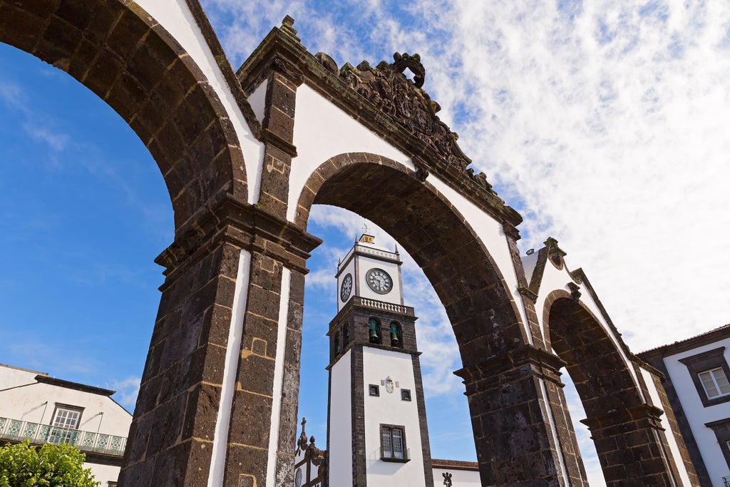 Historic cobblestone street in Ponta Delgada, Azores, lined with whitewashed buildings, ornate colonial architecture, and vibrant blue hydrangeas in full bloom.