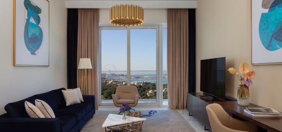 Luxurious sea view apartment with modern decor, floor-to-ceiling windows, king bed, sleek living area, and elegant bathroom in Dubai hotel suite