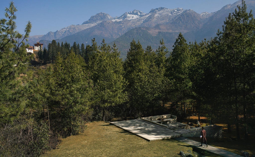 Luxurious mountain lodge with traditional Bhutanese architecture nestled among pine forests, featuring stone facade and panoramic valley views