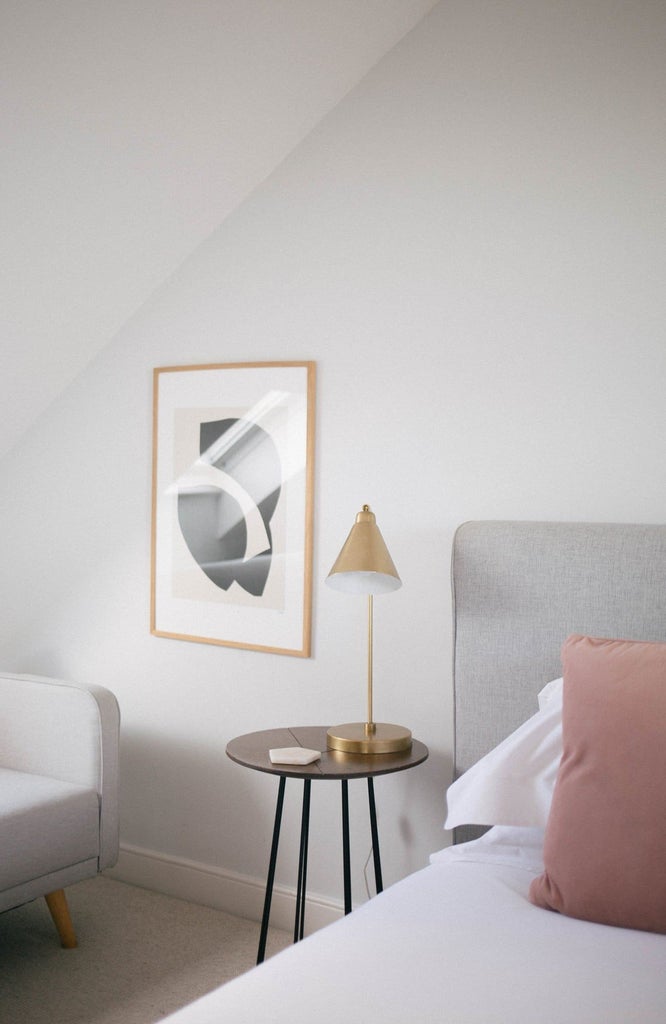 Elegant coastal-style bedroom with plush white bedding, soft neutral tones, nautical artwork, and panoramic sea view through large windows at The Sandy Duck hotel