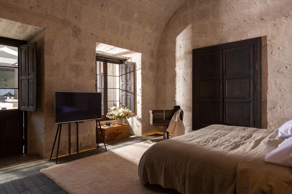 Elegant stone archways frame whitewashed colonial courtyard in luxury Cirqa hotel, with potted plants and period lanterns in Arequipa, Peru