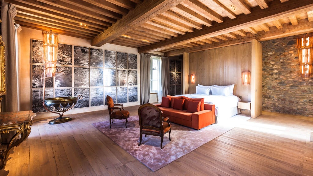 Luxurious French countryside suite with rustic wooden floors, elegant white linens, and panoramic windows overlooking verdant landscape at Domaine des Etangs