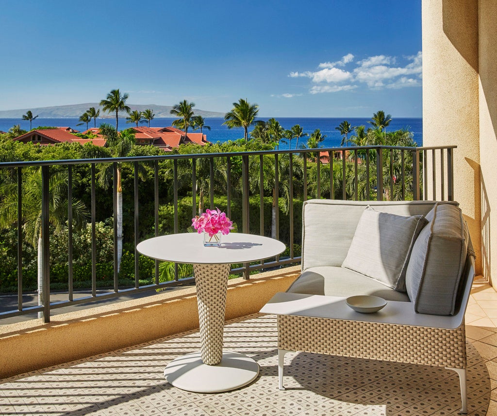 Beachfront luxury resort with infinity pools overlooking Pacific Ocean, white cabanas, and swaying palm trees against Maui's mountains