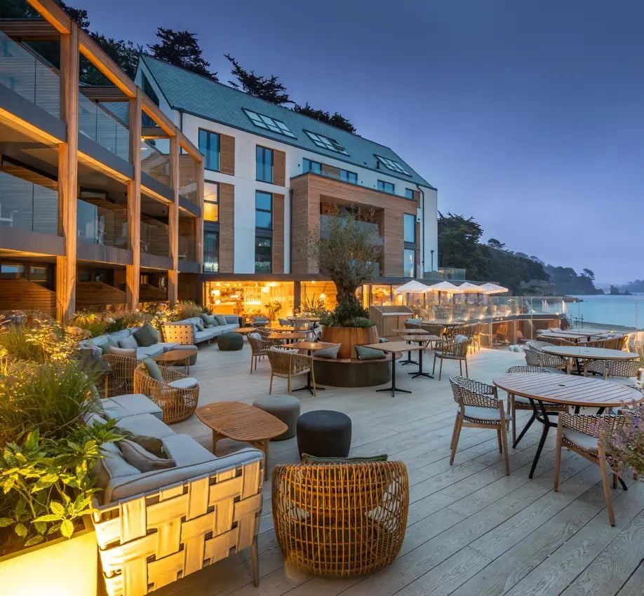 Luxurious waterfront hotel with modern architecture, featuring sleek glass facades and contemporary design overlooking Southampton's scenic harbour at twilight