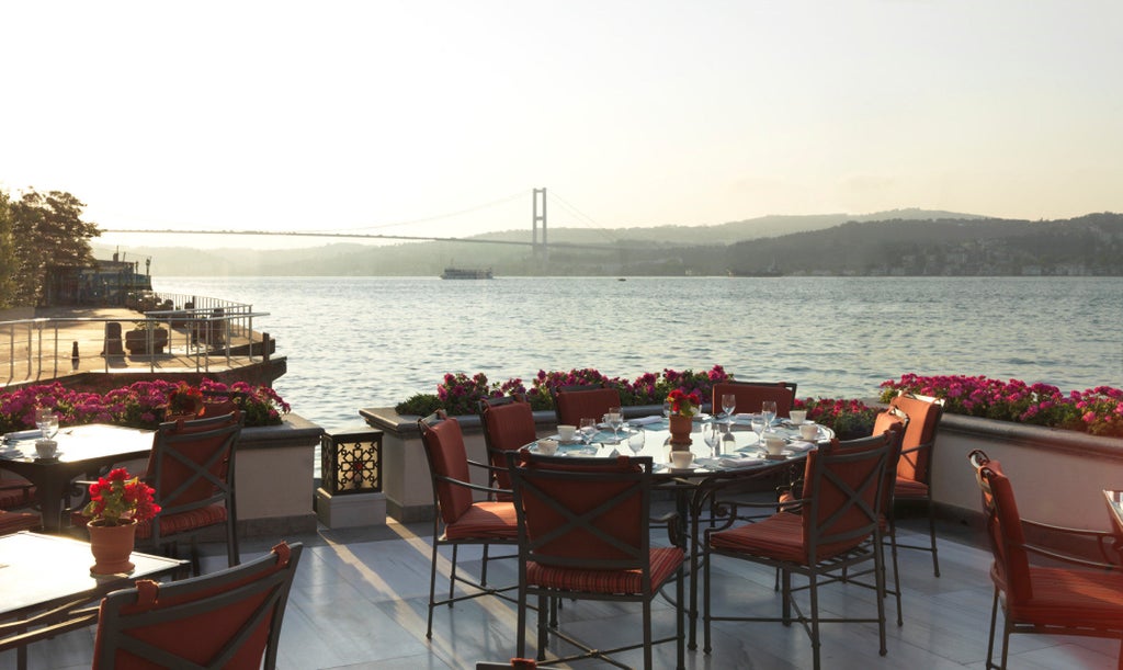 Elegant waterfront hotel with neoclassical facade and ornate gardens overlooking the Bosphorus strait in Istanbul at sunset