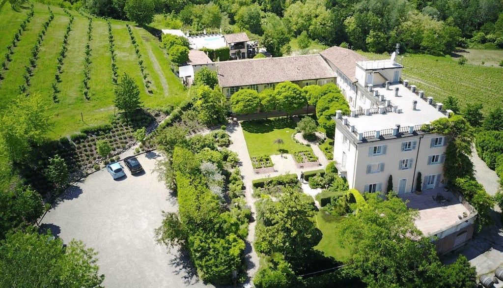 Elegant Italian hotel facade with cream-colored exterior, arched windows, and lush greenery, showcasing Mediterranean architectural charm in scenic scenset landscape