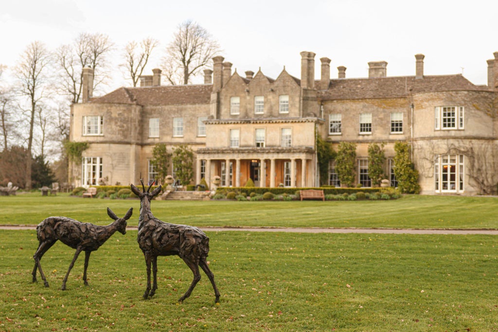 Elegant Palladian-style mansion surrounded by lush gardens, showcasing a grand stone facade with manicured lawns and classic architectural splendor at a luxurious countryside estate