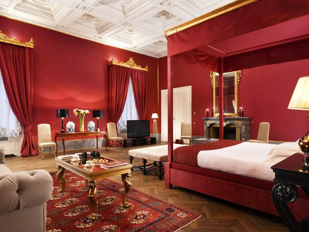 Elegant junior suite with ornate frescoed ceiling, antique furnishings, and plush king bed in historic Palazzo di Camugliano, Tuscany, Italy