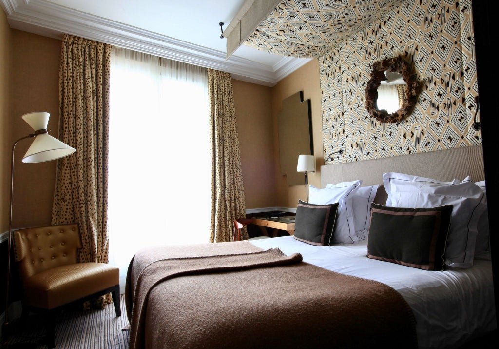 Elegant Parisian deluxe hotel room with soft neutral tones, plush bedding, refined furnishings, and subtle luxurious Récamier-style design elements