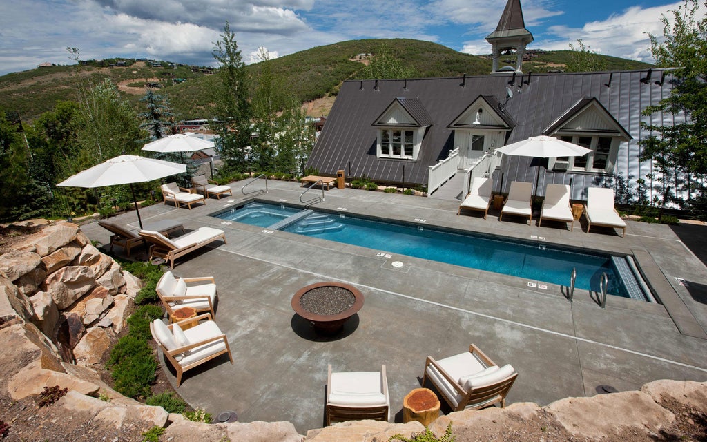 Historic stone schoolhouse turned luxury boutique hotel with grand white columns, arched windows and elegant hanging lanterns in Park City