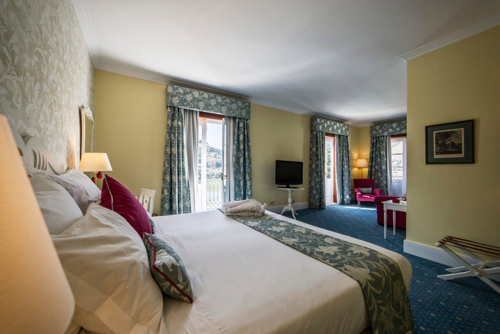 Elegant junior suite with vintage-inspired decor, warm wood furnishings, plush king bed, and panoramic view of Portuguese countryside through large windows