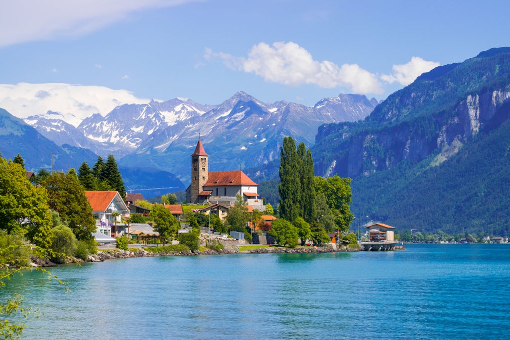 Dramatic aerial view of Interlaken town nestled between emerald lakes, surrounded by snow-capped Swiss Alps at sunset