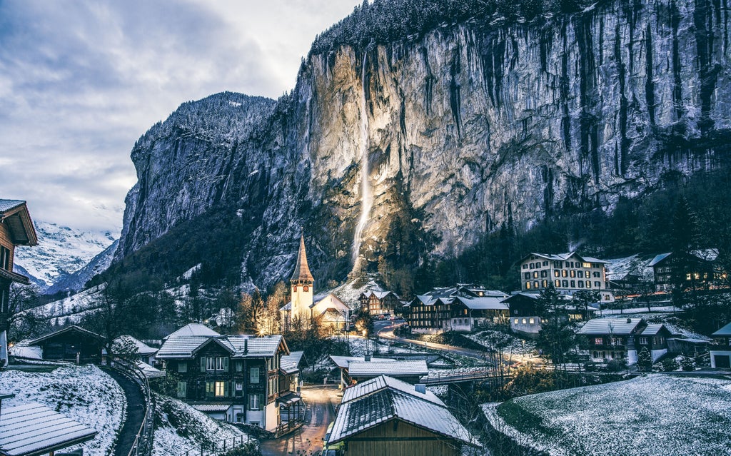 Snow-capped Alpine peaks surround Interlaken's pristine lakes, luxury hotels, and paragliders soaring above Swiss chalets in lush valley