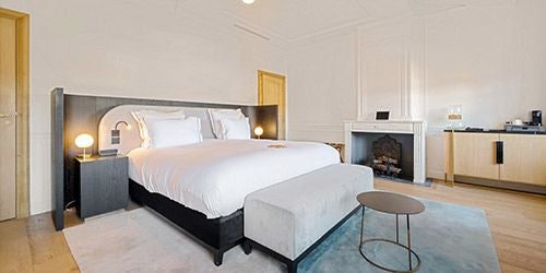 Elegant deluxe hotel room at Château de la Gaude, featuring plush white linens, soft lighting, and panoramic views of French countryside landscape