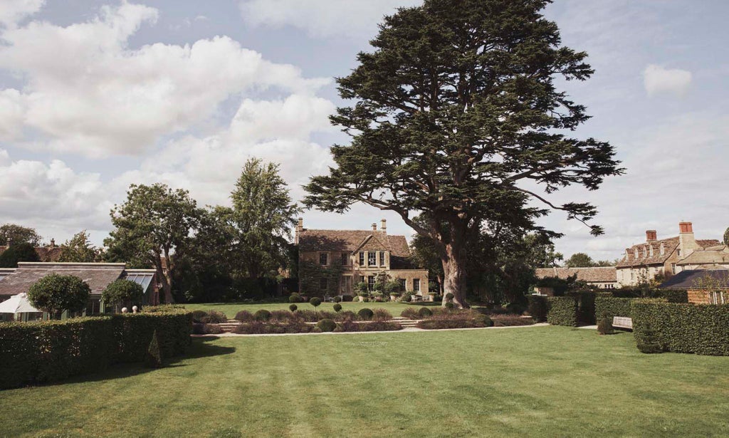 Elegantly styled hotel room with English rose-patterned textiles, rich cedar wood furnishings, and soft neutral tones creating a luxurious, tranquil UK countryside retreat