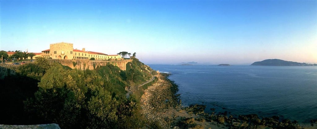 Historic stone fortress hotel perched on rocky peninsula overlooking the Atlantic, featuring medieval architecture and panoramic bay views