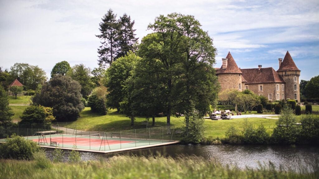 Luxurious French countryside château with stone walls, surrounded by lush green meadows and tranquil reflecting ponds at golden hour