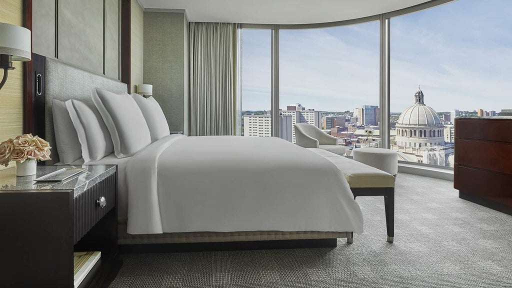 Luxurious back bay corner suite with modern decor, panoramic city views, plush king bed, elegant marble bathroom, and sophisticated seating area at Four Seasons Hotel