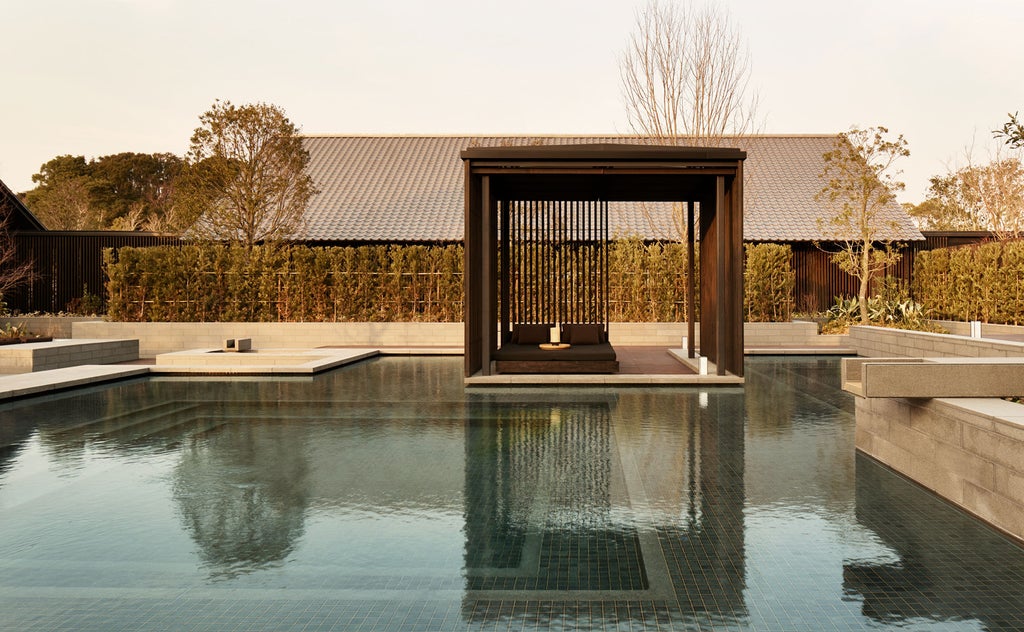 Modern Japanese resort villa with private onsen bath overlooking lush mountains, featuring minimalist design and natural wood elements