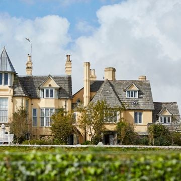 Rustic-chic countryside hotel with stone exterior, lush gardens, and vintage windows, embodying a quintessential British rural luxury retreat nestled in scenic landscape