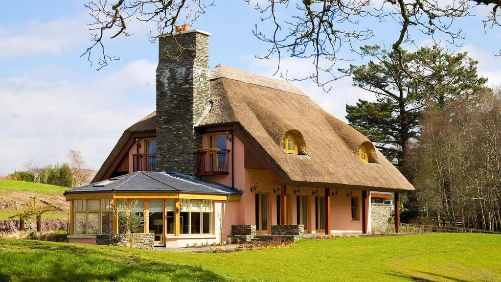 Elegant cottage bedroom with soft lighting, king bed with white linens, traditional woodwork, and French doors leading to garden view