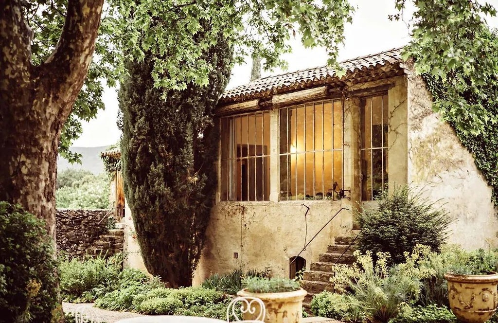 Elegant stone facade of Le Galinier hotel with warm terracotta roof, surrounded by lush Provençal lavender fields at golden sunset