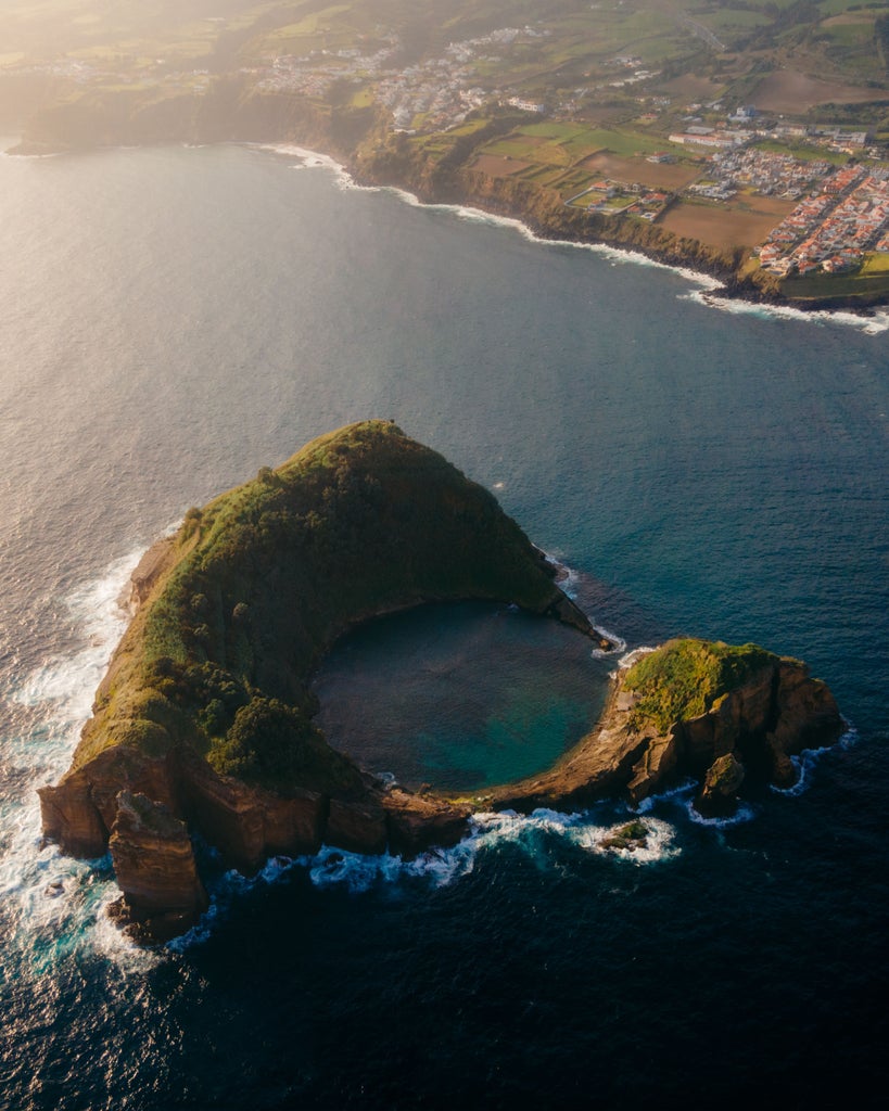 Aerial view of Vila Franca Islet, São Miguel, Azores: circular volcanic crater with turquoise waters, lush green cliffs, and pristine natural swimming pool