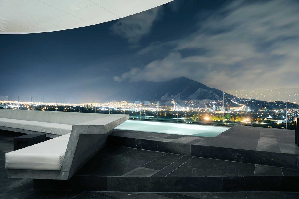 Modern glass-and-steel luxury hotel with sleek architectural design overlooking Monterrey's skyline, featuring minimalist lines and contemporary urban aesthetic at dusk