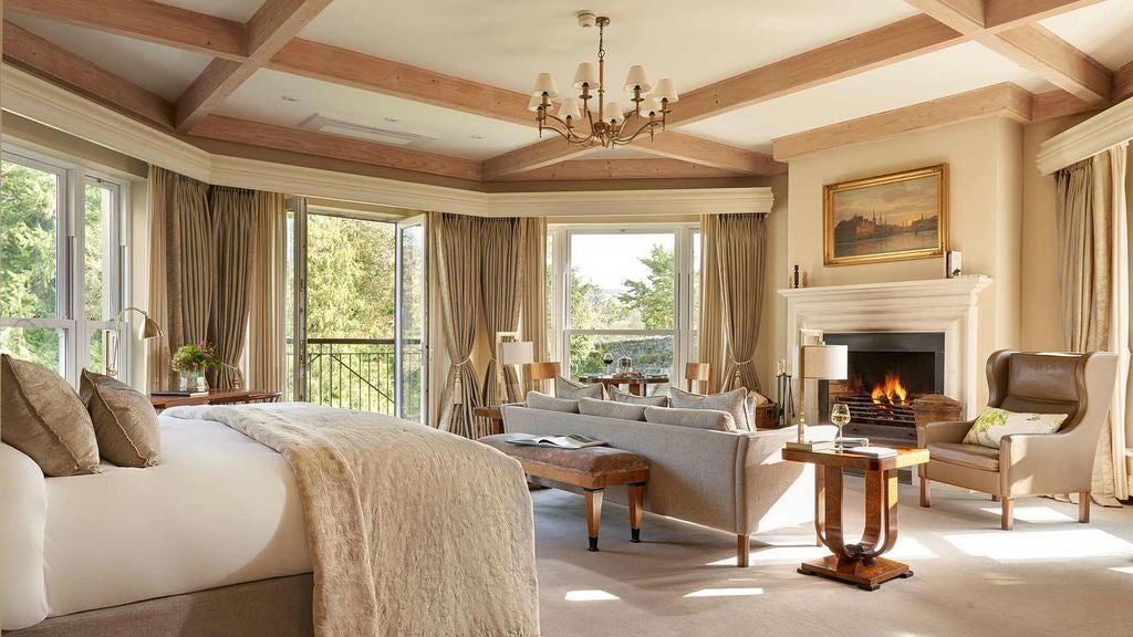 Elegant suite with plush king bed, crystal chandelier, antique furnishings and large windows overlooking Irish countryside at Sheen Falls Lodge