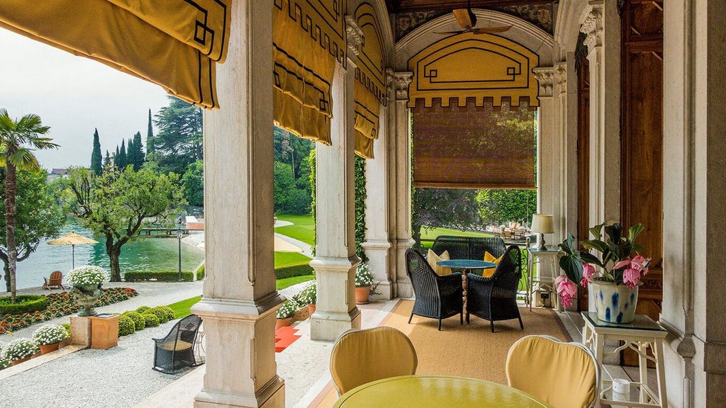 Art Nouveau-style luxury hotel Villa Feltrinelli with pink facade, ornate balconies and manicured gardens along Lake Garda in Italy