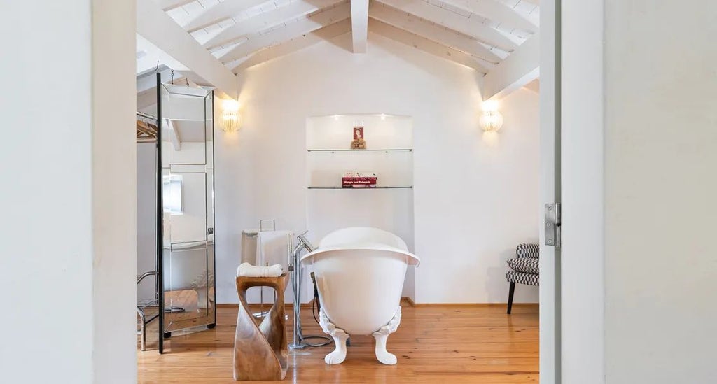 Spacious, elegant suite with rustic wooden furniture, plush white bedding, and panoramic countryside views in a traditional Portuguese country house