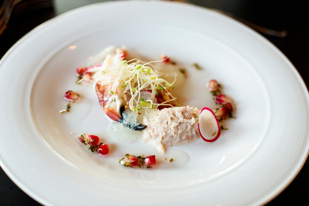 Intimate gourmet lunch on a secluded Norwegian islet, pristine waters surrounding wooden deck with elegant table setting and minimalist Scandinavian design