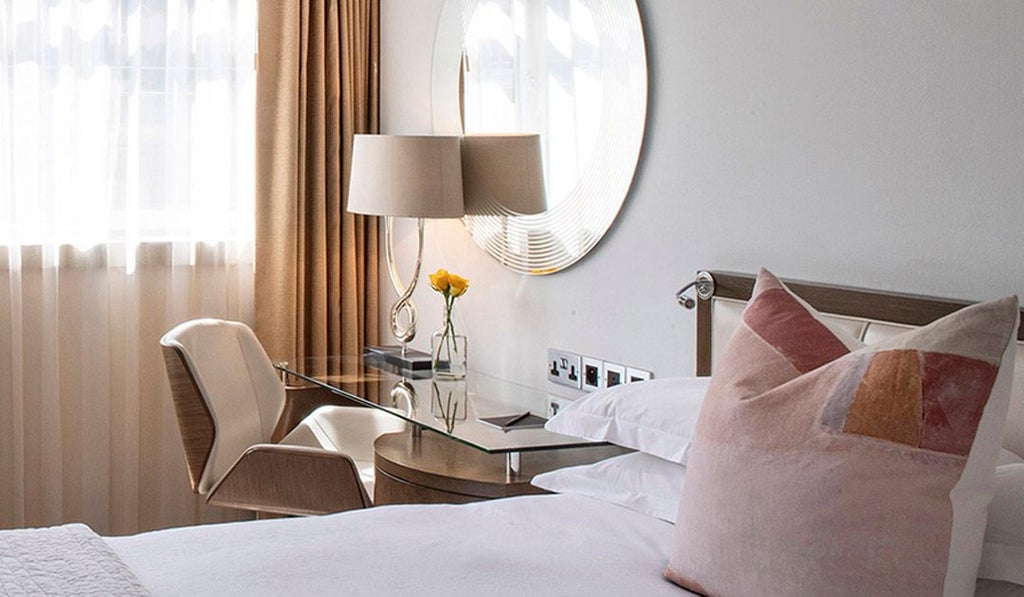 Elegant classic hotel room with plush queen bed, soft neutral tones, contemporary furnishings, and sophisticated lighting in a boutique UK accommodation setting